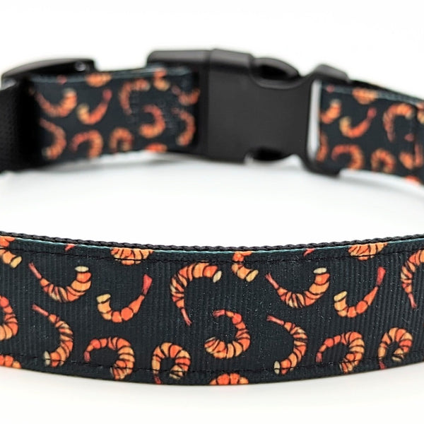 Dog collar with black background and red and orange shrimp pieces on it