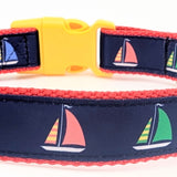 Sailboat dog collar made from navy blue nylon webbing with yellow, green, and red sailboat ribbon. Features a yellow plastic side-release buckle and red nylon webbing.
