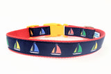 Sailboat dog collar made from navy blue nylon webbing with yellow, green, and red sailboat ribbon. Features a yellow plastic side-release buckle and red nylon webbing.