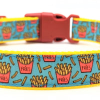 Dog collar with turquoise ribbon with yellow french fries in a red package. Dog collar has yellow nylon under the turquoise ribbon and a red plastic buckle.
