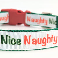 Dog collar with white ribbon and text in red that says Naughty and text in green that says Nice. Collar has a red buckle and has green nylon underneath the red ribbon. Set on a white background.