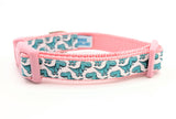 Dog collar featuring seafoam green cartoon T-Rex dinosaurs on a white ribbon, sewn onto light pink nylon webbing and with a light pink side-release buckle.