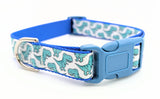 Dog collar featuring seafoam green cartoon T-Rex dinosaurs on a white ribbon, sewn onto royal blue nylon webbing and with a blue side-release buckle.