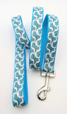 Dog leash featuring seafoam green cartoon T-Rex dinosaurs on a white ribbon, sewn onto turquoise nylon webbing.