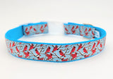 Handmade Winter Cardinal dog collar featuring red birds on snowy branches ribbon against a light blue nylon background.