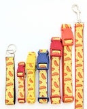 Assortment of XS to Large dog collars in yellow hotdog ribbon with red accents shown on different webbing backing colors and key fob and leash also